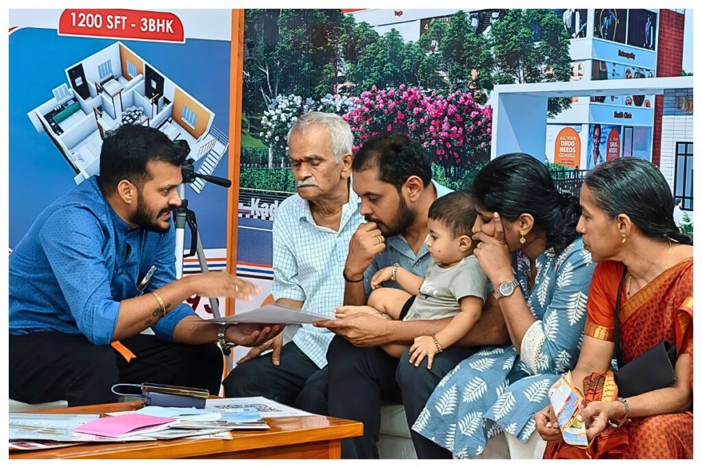 Family discussing senior living township options with a Dwaraka representative using layout plans of Ujjeevana.